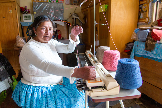 Estela Castillo sets-up the knitting machine she bought with a loan from Oikocredit’s partner, Crecer.